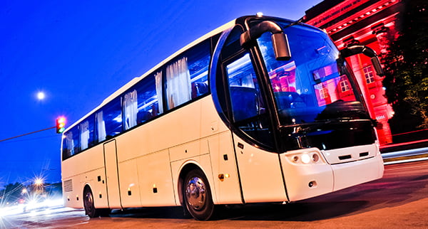 a 56 passenger motorcoach on a city street at night