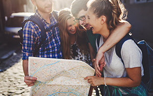 a group of sightseers embrace and laugh while holding a map